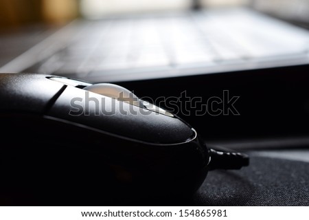 Computer mouse and laptop in background with shallow depth of field