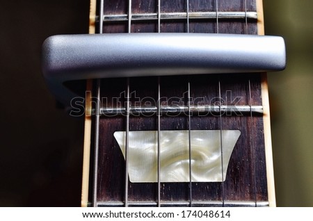 Guitar neck with frets, strings and capo.