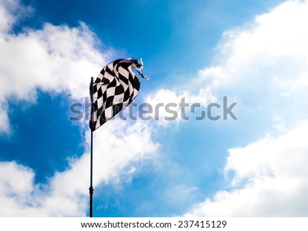 Weather-beaten Grand Prix checkered flag against cloudy blue skies