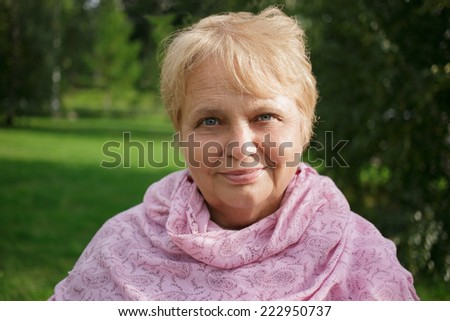 Portrait of happy pretty senior woman in the park on nature background
