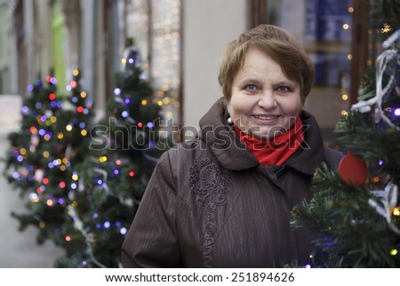 Portrait of a senior woman over vivid winter lights. Focus on woman\'s face.