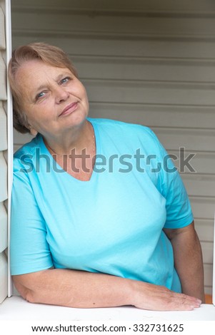 Calm and peaceful pensioner woman at window in dacha