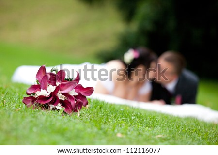 Young marrieds behind a wedding bouquet