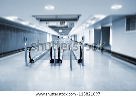 A view along a long moving walkway or moving sidewalk commonly used at modern airport terminals.