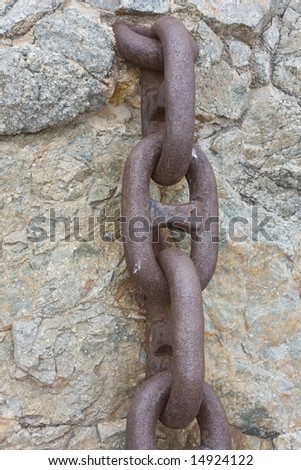 link chain is hanging on old stone wall