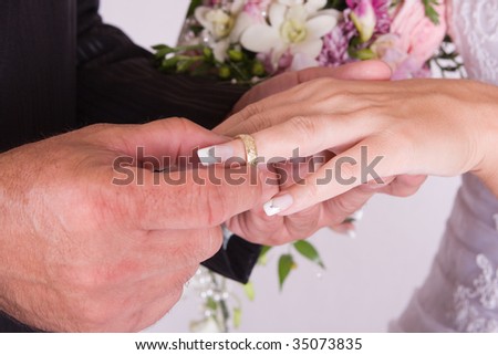 Groom Putting Wedding Ring on Bride`s Finger - studio photo