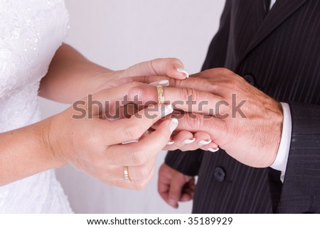 Bride Putting Wedding Ring on Groom`s Finger - studio photo