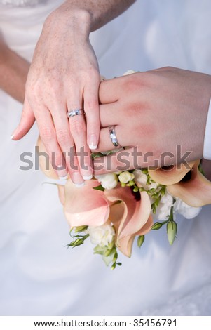 newly married - hands with silver rings on a beautifull wedding bouquet