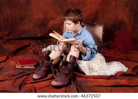 a boy wearing old shoes is sitting in a case and reading a book