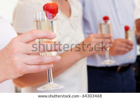 People holding cold champagne glasses with strawberries
