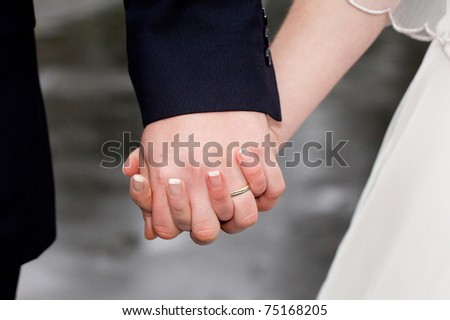  closeup of holding man's and woman's hands wearing wedding ring