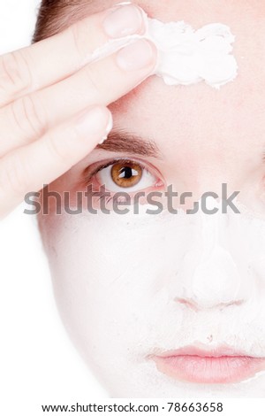 Beautiful young woman doing cosmetic mask on her face - white background