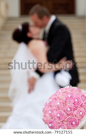 Young marrieds behind a wedding bouquet