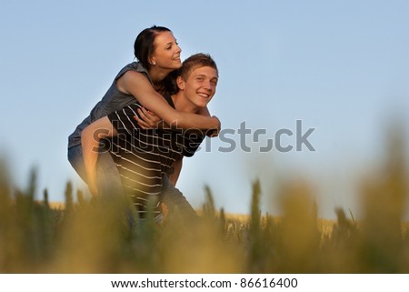 A young sweet couple in love - the boy as carried the girl on his back