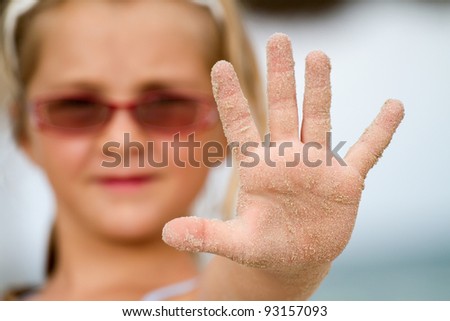 A childs hand with grains of sand and dirt, in the stop position, focus on the hand