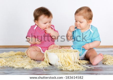 Messy baby toddlers having fun eating pasta