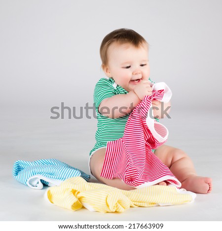 Portrait of smiling 10 months baby girl choosing clothes