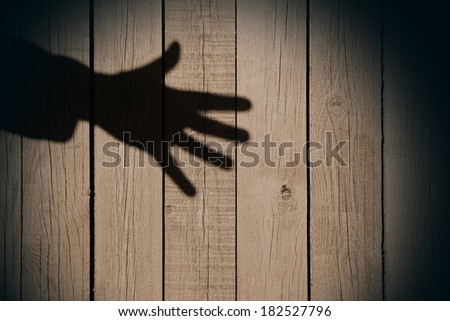Human hand opened up flat in shadow on the wood background, with space for text or image.