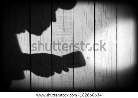 Unrecognizable burglar with  flashlight  in shadow on wood background, with space for text or image