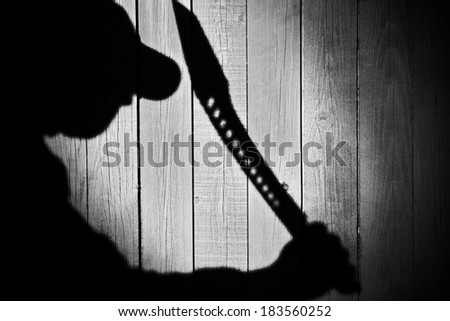 Human Silhouette with Machete in Shadow on wooden background, with space for text or image. You can see more silhouettes and shadows on my page.