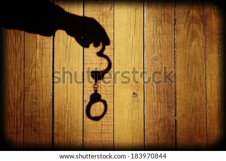 Male Hand with Handcuffs on Natural Wood Background. You can see more silhouettes and shadows on my page.