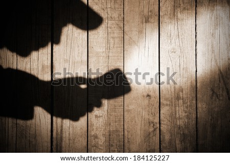 Detective Silhouette with a searchlight on Grungy Wooden Background.