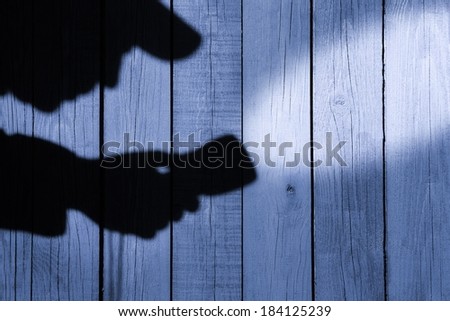 Silhouette with a Searchlight on Grungy Wooden Background.