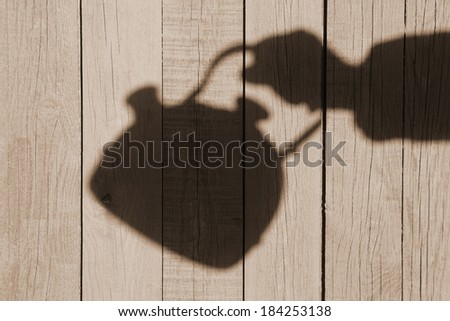 Hand Shadow with Kettle on the Natural Wooden Background, with space for text or image