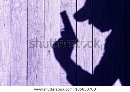 Man with a gun in shadow on a wooden background. You can see more silhouettes and shadows on my page.