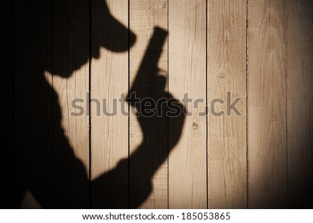 Gangster or investigator or spy silhouette on natural wooden wall. You can see more silhouettes and shadows on my page.