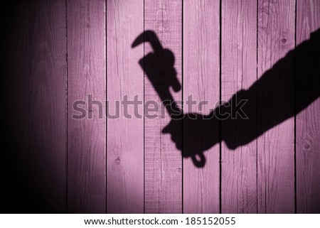 Human hand shadow with adjustable wrench  on the wood background, with space for text or image. You can see more silhouettes and shadows on my page.