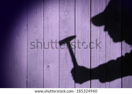 Shadow of a man with hammer in hand on natural wooden background. You can see more silhouettes and shadows on my page.