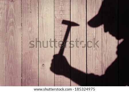 Shadow of a man with hammer in hand on natural wooden background. You can see more silhouettes and shadows on my page.