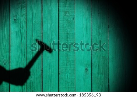 Shadow of a hand with hammer on natural wooden background. You can see more silhouettes and shadows on my page.