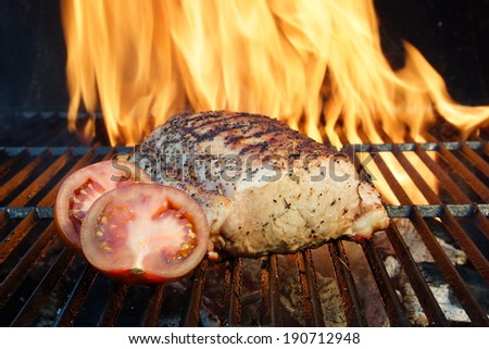 Grilled pork ribs and tomatoes on the BBQ grill, flame background, with space for text or image.