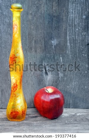 Bottle of liquor and apple on a wooden background with space for text or image.