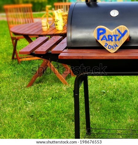 BBQ Summer Garden Party Scene with sign PARTY 2014 on wooden heart and tilt shift effect in background