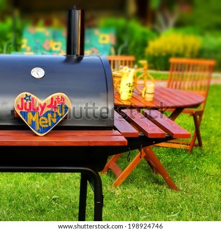 BBQ Summer Backyard Party Scene with sign JULY 4 th MENU on wooden heart. Tilt-Shift effect on background.