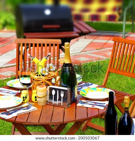Outdoor Dining or Party Scene in Backyard. BBQ Grill in background. Tilt-shift effect.