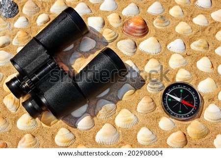 Vintage Binoculars, Compass and Seashells on a Beach Sand close-up. Summer Marine background with space for text or image