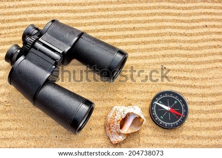 Sea Binoculars and Compass isolated on the sand background