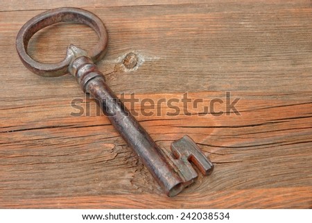Old Rusty Iron Key on a Wooden Background