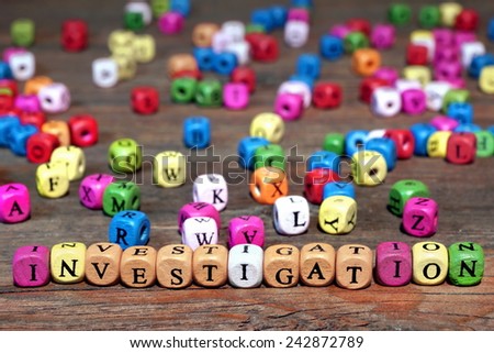 Sign INVESTIGATION and many colored cubes with letters on wooden table