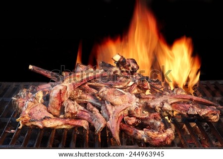 Marinated Lamb Ribs in BBQ Souse on the Hot Grill. Flame of Fire on the Black Background