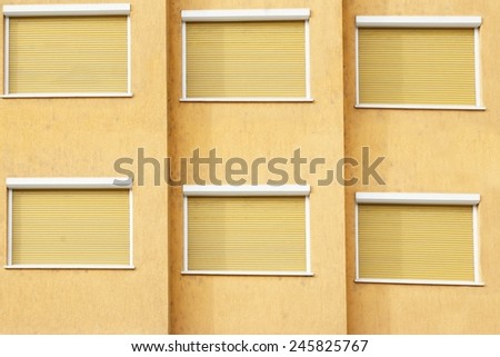 Yellow Building Facade with Six Closed Windows Shutters Background with Space for Text or Image