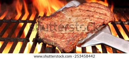 BBQ Roasted Beef Steak on the Turner and Flaming Charcoal Grill