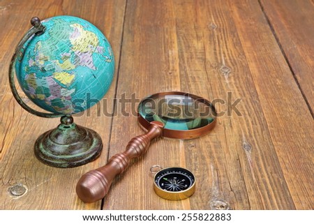 Vintage Globe Map, Compass,  and Magnifying Glass On Grunge Wood Table