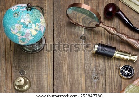 Retro Travel And Adventure Objects On The Wooden Grunge Table Background.  Compass, Globe Map, Bell,  Spyglass, Two Vintage Notebooks In The Right Corners, Smoking Pipe, Magnifying Glass