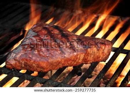Marinated Beef Steak On The Hot BBQ Charcoal Grill. Flame Of Fire In The Background.
