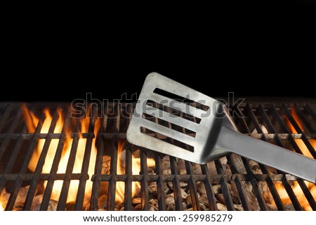 BBQ Grill And Spatula. Flame Of Fire In The Background.